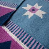 Detail of flatweave runner rug, handwoven from wool in blue, navy and pink with a geometric design inspired by Victorian tiles.