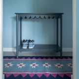 Light blue hallway with Blue Runner Rug, handwoven with a geometric zig zag border and star motifs and magenta pink accents.