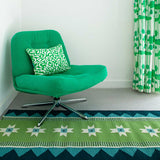 Vibrant geometric green runner rug in a colourful living room with green armchair and green printed curtains.