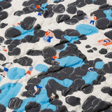 Detail of the Rockpool baby quilt handprinted and hand quilted, with playful illustrations of families enjoying the beach and seaside.