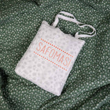 The Green Pine baby quilt in a cotton bag embroidered with the Safomasi logo, ready to gift.